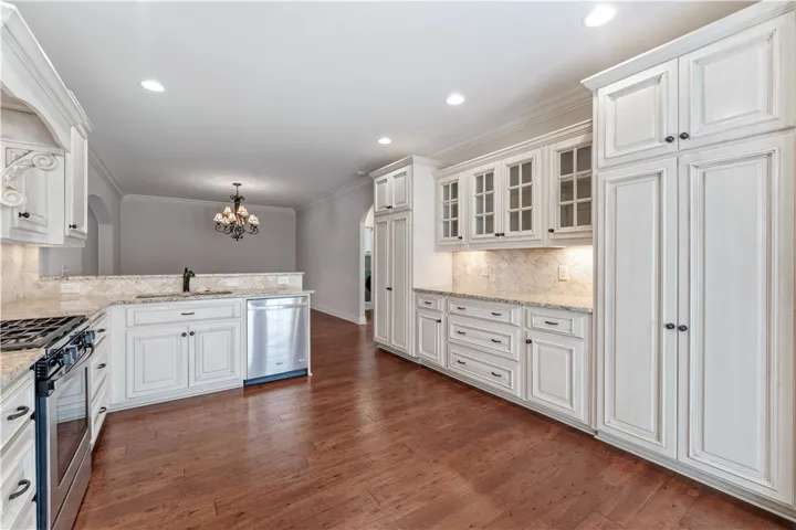 A well-appointed kitchen features rich hardwood flooring and white cabinetry, providing both elegance and practicality.