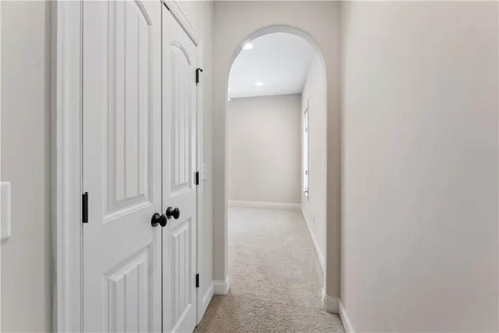 An inviting hallway with an arched doorway leads to a well-lit interior, complete with a functional storage closet.