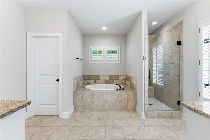 Unwind in a luxurious primary bathroom featuring a spacious soaking tub and a sleek, tiled walk-in shower.