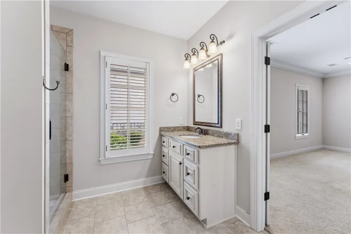 A well-appointed bathroom features a single vanity with granite counters and a shower stall.