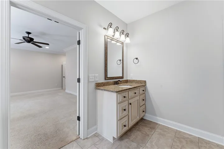 A well-appointed vanity with a granite countertop and ample storage complements the tiled flooring.