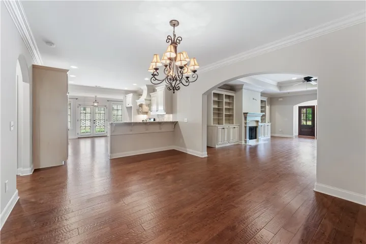Elegant hardwood flooring extends through this open concept living space, anchored by a prominent fireplace with built-in shelving.