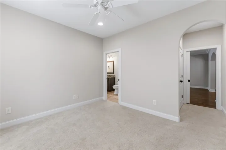 A well-lit bedroom features plush carpeting and an adjoining private bathroom.