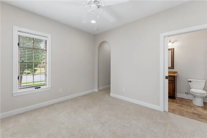Well-lit room with plush carpeting offers tranquil views of green landscaping.