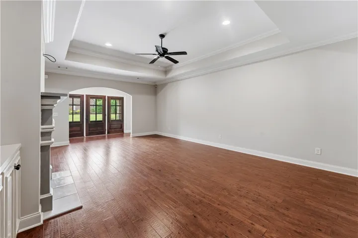 Rich hardwood floors complement elegant tray ceilings, enhancing this spacious living area.