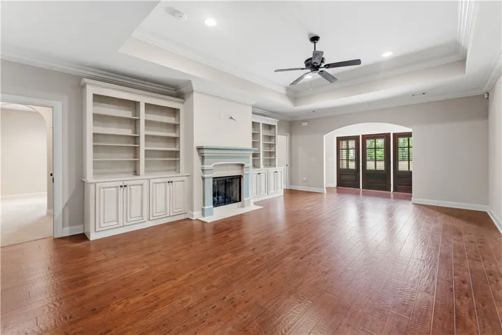 A refined living space showcases rich hardwood floors, a cozy fireplace with built-in shelving, and direct outdoor access through French doors.