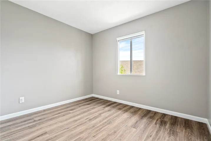 A well-lit bedroom with durable wood flooring and ample natural light.