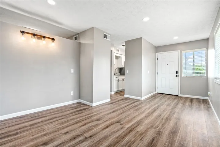 Laminate wood flooring sweeps across the open-concept living space, leading to a contemporary kitchen.