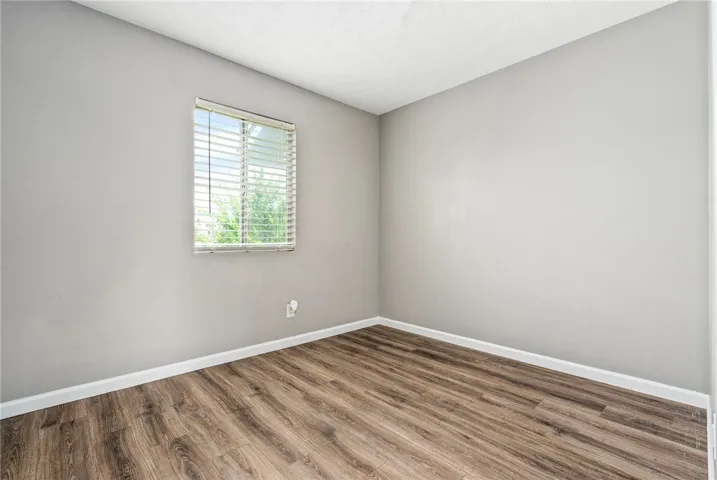 Well-lit room featuring durable wood-like flooring and a window with horizontal blinds.