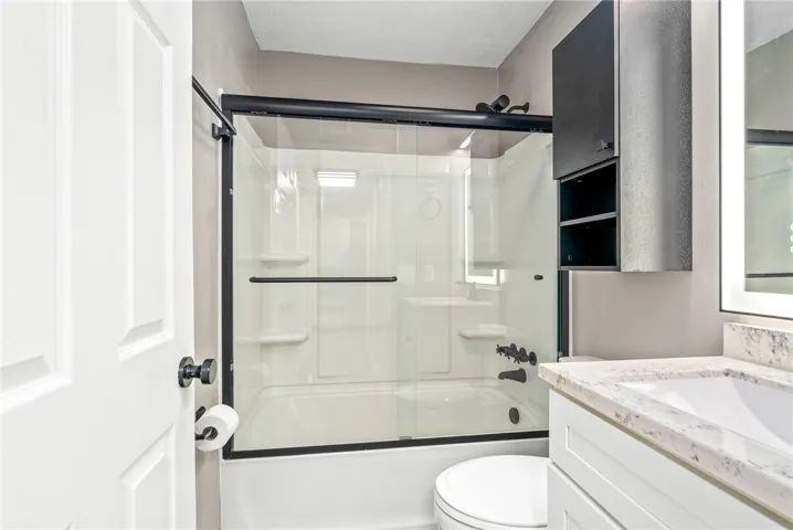Refined primary bathroom featuring a full bathtub with shower and a sleek vanity with stone counters.