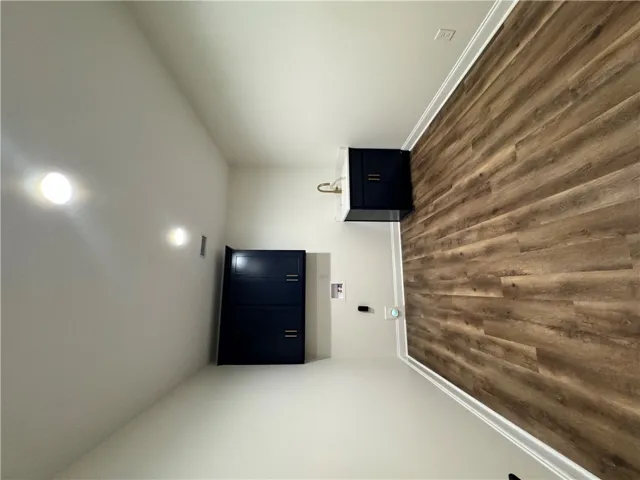 Functional laundry space featuring durable wood flooring and ample built-in cabinetry.