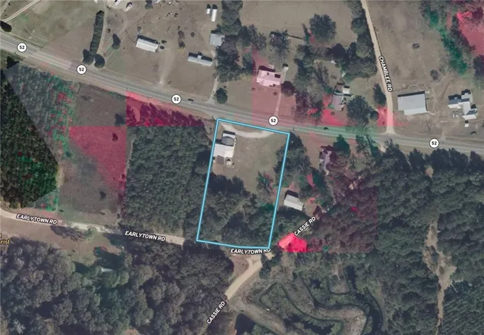 An aerial perspective reveals the property's expansive lot, surrounded by mature trees and convenient road access.