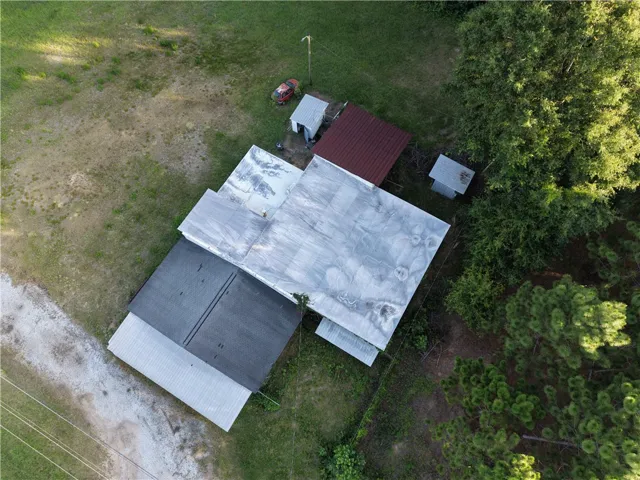 Aerial view showcasing a tranquil rural setting with mature trees and a gravel driveway.