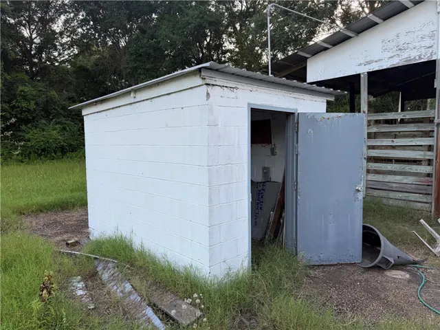A sturdy white block storage building stands amidst a grassy rural setting, providing practical outdoor utility.
