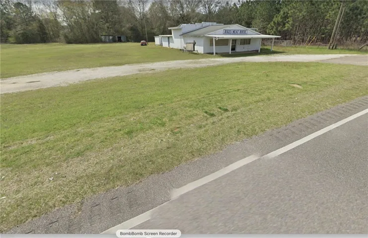 A commercial property featuring a main structure with an adjacent open lot and a gravel driveway.