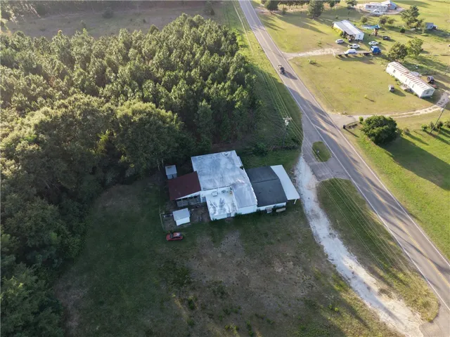 An aerial perspective reveals a secluded structure nestled amidst verdant forestry and open land.