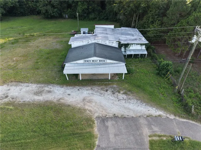An aerial perspective reveals a commercial structure with a covered entrance and surrounding green space.