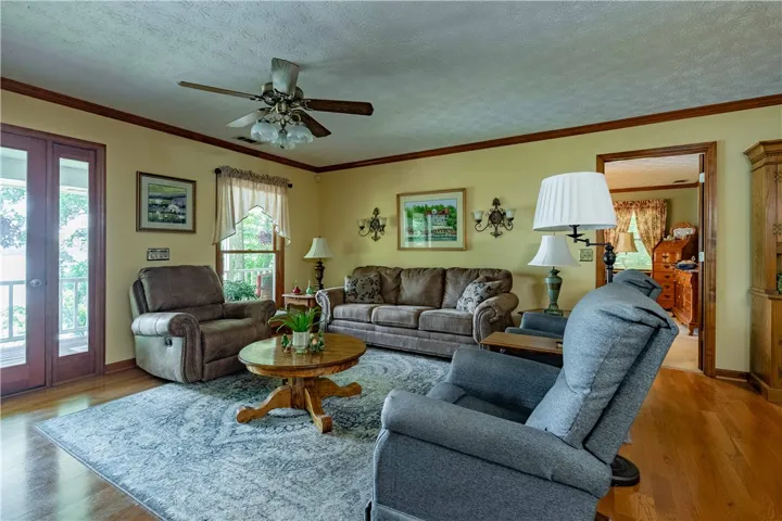 Well-lit living area showcases rich hardwood flooring and a functional ceiling fan for comfort.