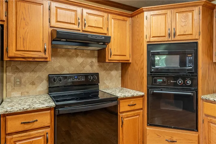 A well-appointed kitchen features ample wood cabinetry, granite countertops, and built-in appliances for culinary convenience.
