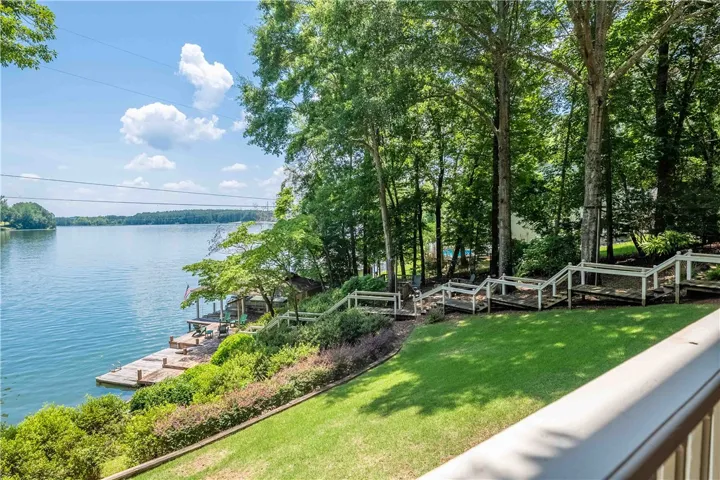 Panoramic lake views from this sloped yard with a private dock and mature trees.