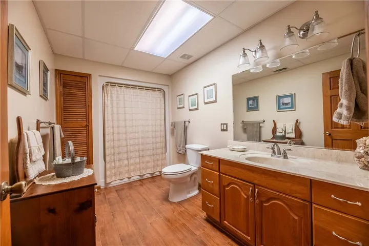 A pristine bathroom featuring rich wooden flooring and a spacious vanity with a broad mirror.