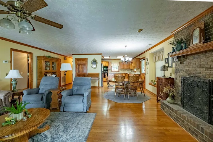 An inviting open-concept living and dining area with warm hardwood floors and a classic brick fireplace.