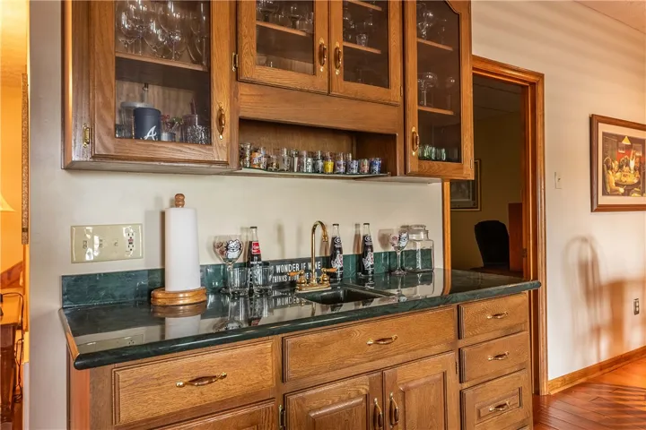 A wet bar with rich wood cabinetry and a deep green countertop creates a perfect entertainment spot.