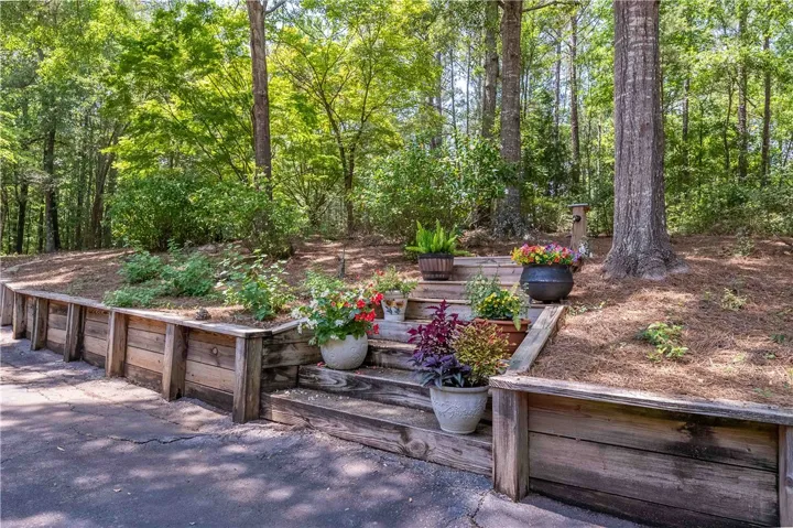 Terraced landscaping with vibrant potted plants ascends towards a natural, wooded backdrop.