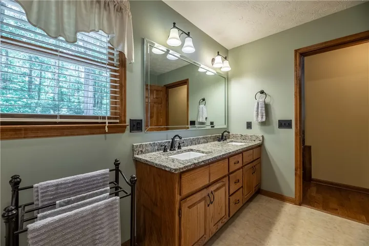 Double vanity with granite counters and rich wooden cabinetry elevates this full bathroom.