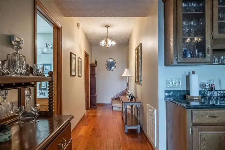 A warm wooden floor hallway connects living spaces, leading to a charming staircase.