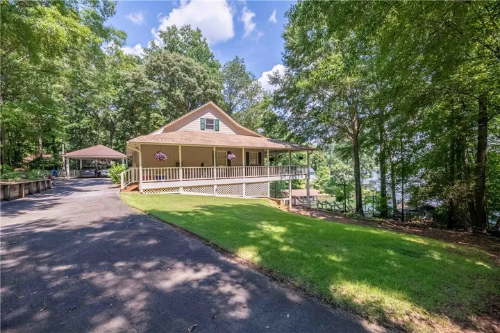 Perched above the lake, this charming residence offers a wraparound porch and a convenient covered carport.