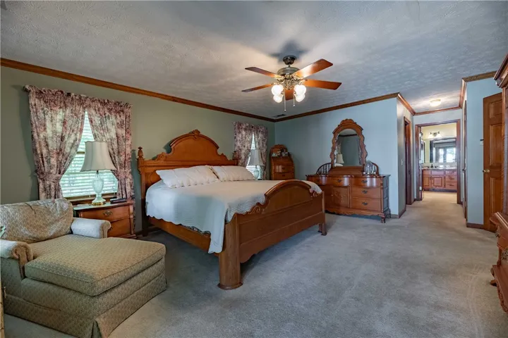 A well-lit bedroom offering a cozy ambiance with a ceiling fan and easy access to an adjoining bath.