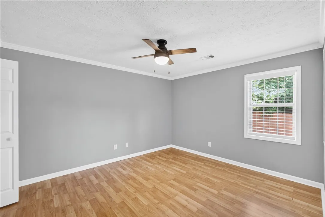 A well-proportioned bedroom with rich wood flooring and natural light invites peaceful living.