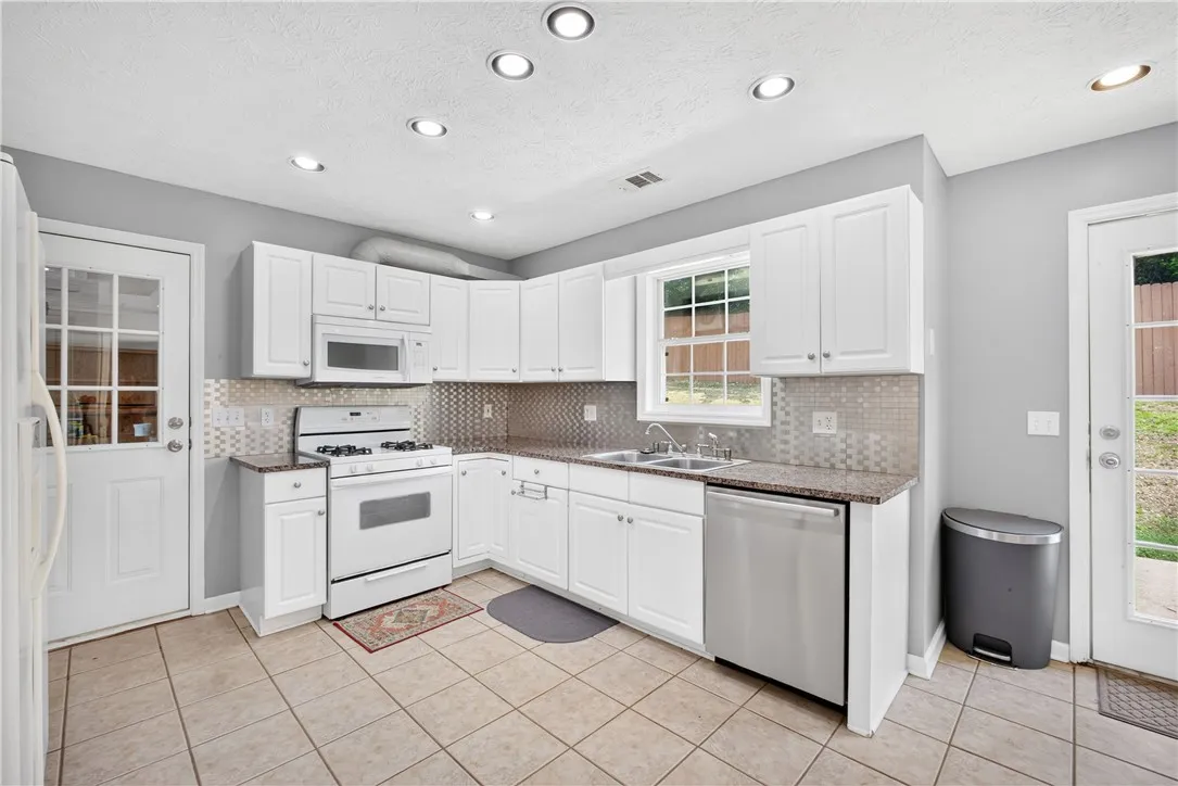 A well-equipped kitchen features ample cabinetry, recessed lighting, and durable tile flooring.