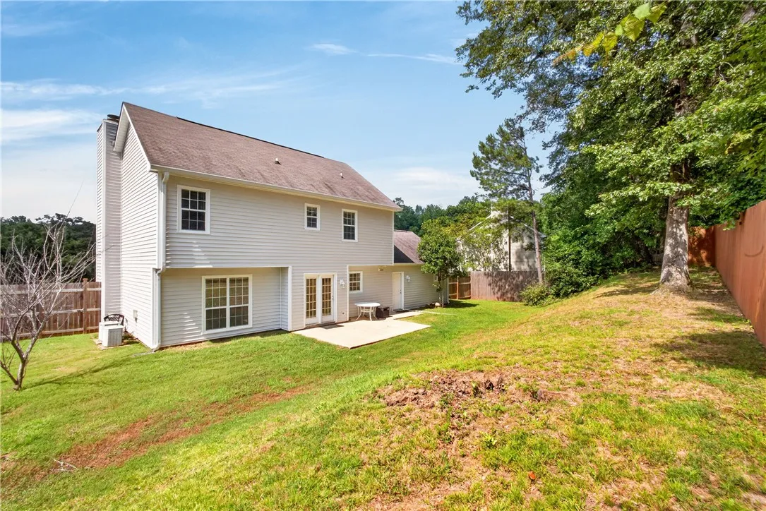 A private backyard awaits, featuring a concrete patio perfect for outdoor enjoyment and verdant landscaping.