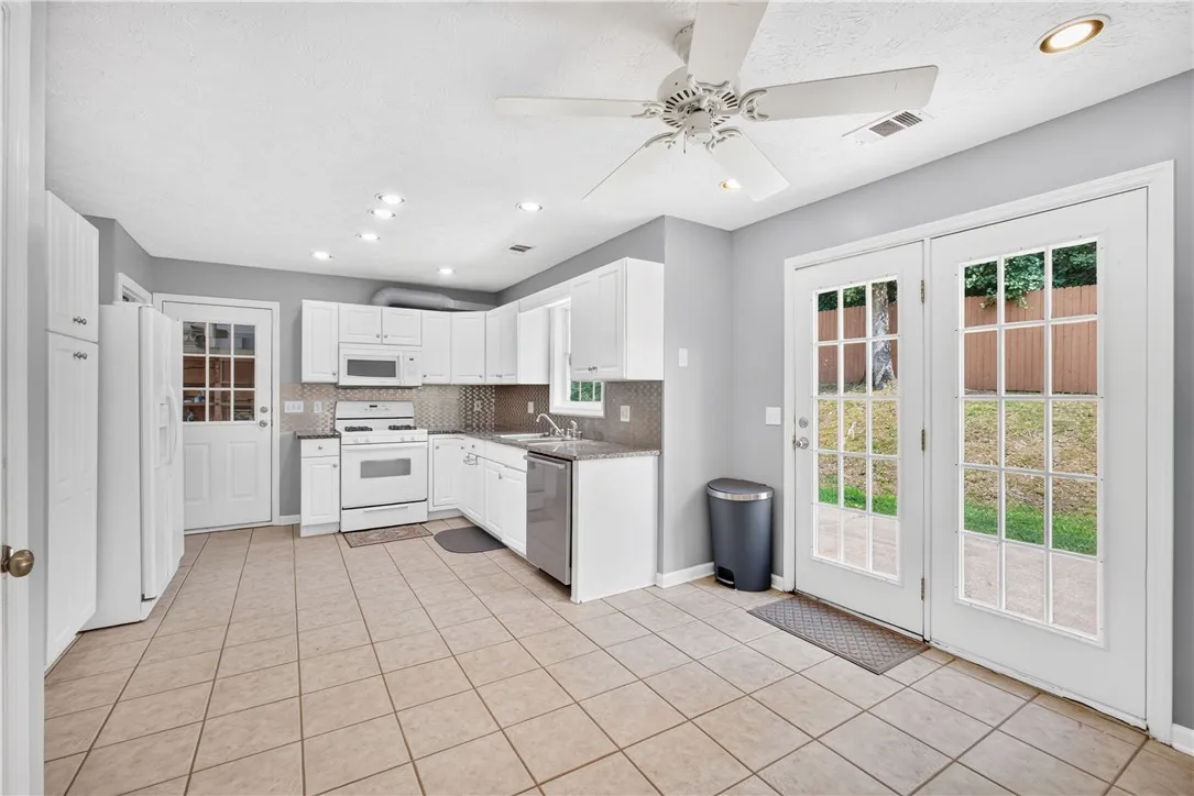 Bright, white cabinetry and appliances complement the warm tiled flooring in this inviting kitchen.