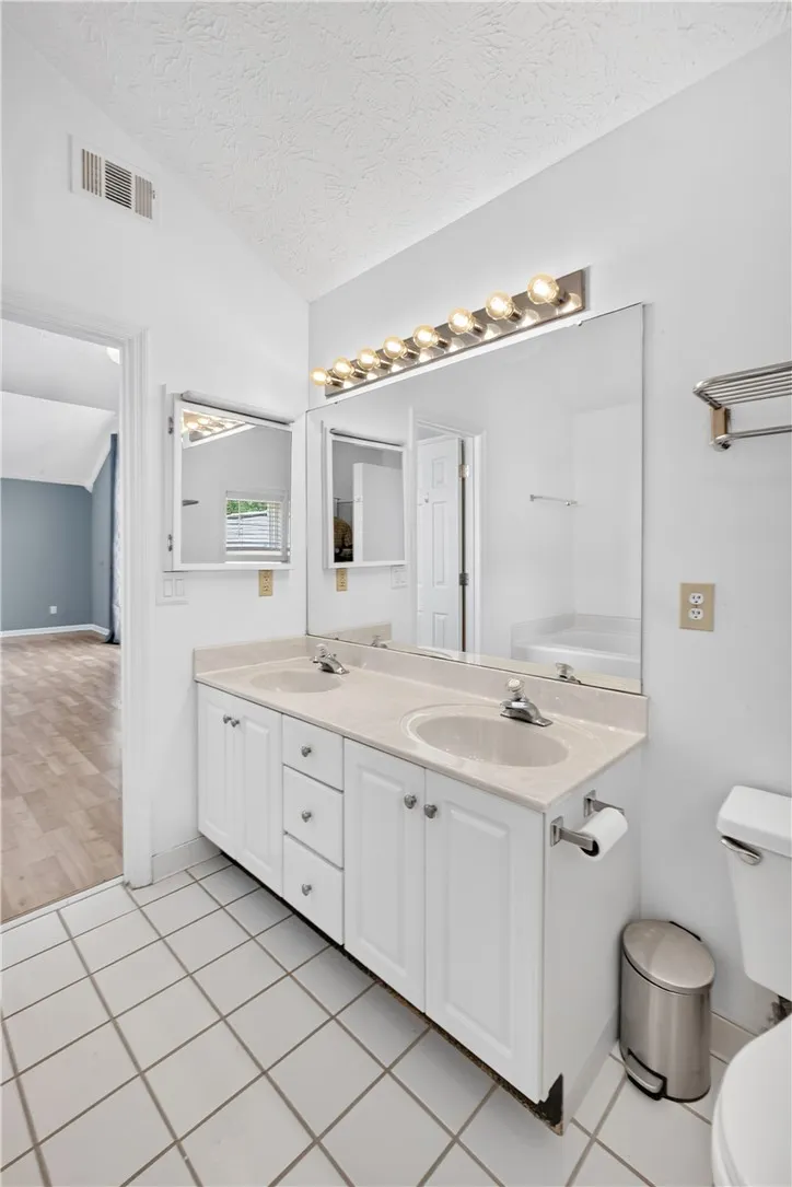 A well-lit bathroom offers a dual-sink vanity and sleek tile flooring.