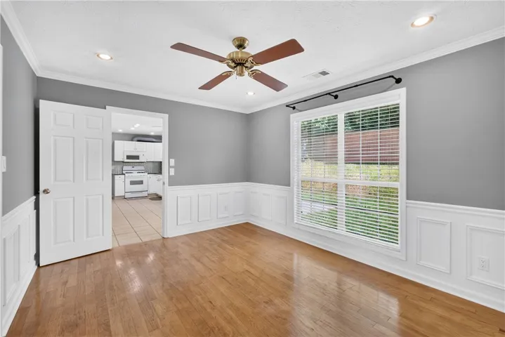 A well-lit room showcases rich hardwood floors and classic wainscoting, offering a welcoming atmosphere.