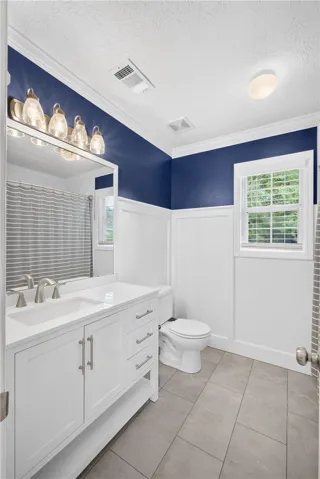 A well-appointed bathroom features a bright vanity, elegant wainscoting, and large windows that invite natural light.