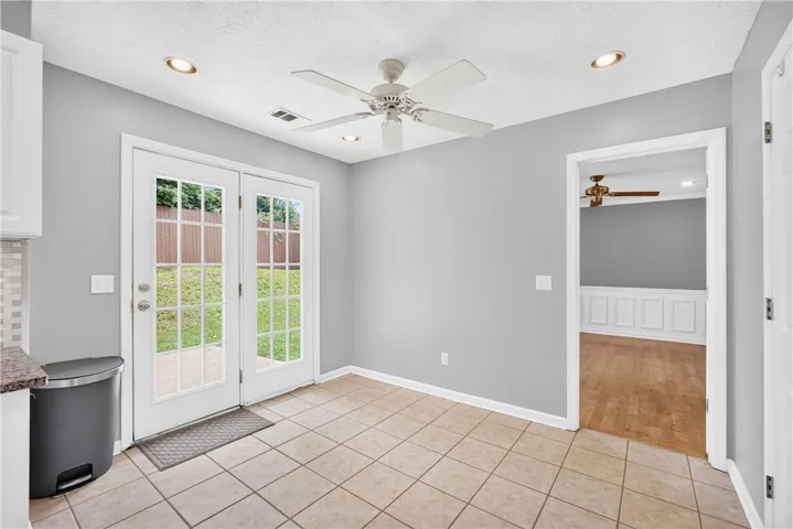 Bright breakfast area features tiled flooring, a ceiling fan, recessed lighting, and direct backyard access through French doors.