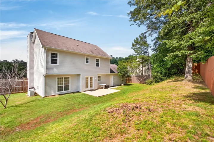 A private backyard awaits, featuring a concrete patio perfect for outdoor enjoyment and verdant landscaping.