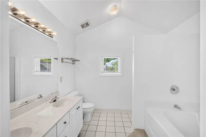 A pristine bath offers dual vanities and a relaxing soaking tub.