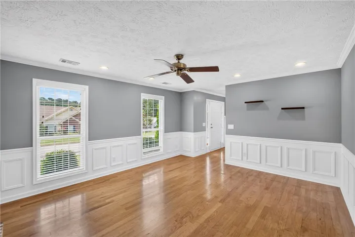 Refined wood flooring complements the bright windows and classic wainscoting in this open living space.
