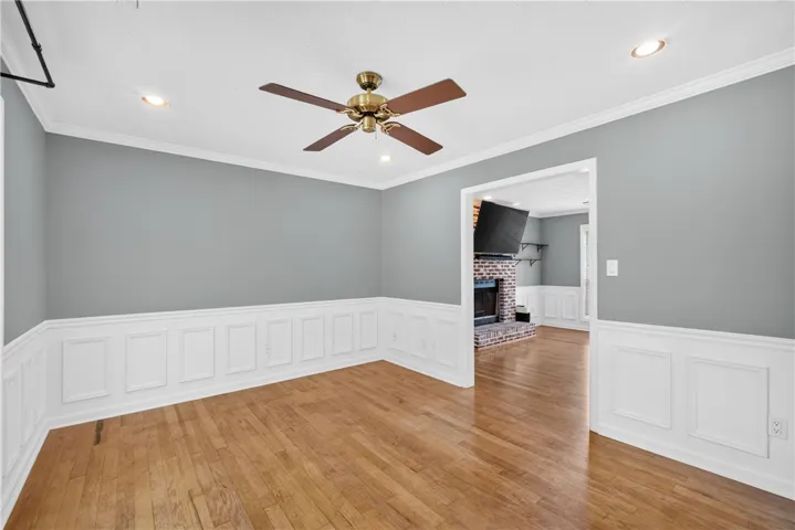 Hardwood floors and wainscoting enhance this elegant room, opening to a cozy living space with a brick fireplace.