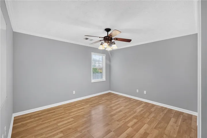 A quiet bedroom with light wood flooring and a refreshing ceiling fan awaits your personal touches.