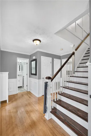 Hardwood flooring extends throughout the entry, complemented by a finely crafted staircase and wainscoting.