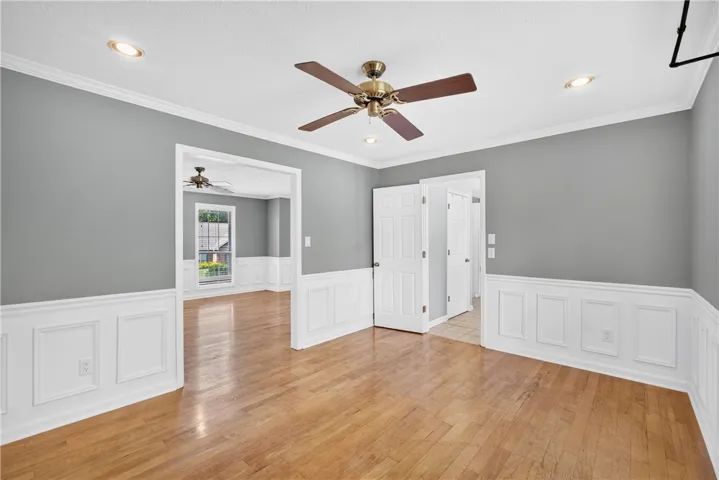 Hardwood flooring extends throughout this versatile space, featuring elegant wainscoting and modern recessed lighting.