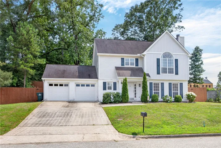 White siding with blue shutters frames a welcoming entry and ample garage space.