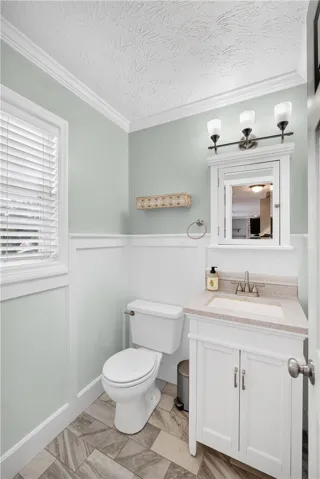 A bright bathroom with wainscoting and a crisp white vanity offers a refreshing private retreat.