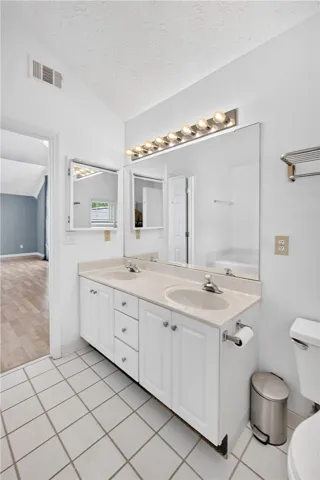 A well-lit bathroom offers a dual-sink vanity and sleek tile flooring.